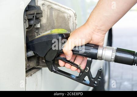 Homme remplissant la voiture de diesel. Main avec distributeur d'huile noir à la station d'essence. Ravitaillement de l'ancienne minifourgonnette euro3 avec du diesel en90. Banque D'Images