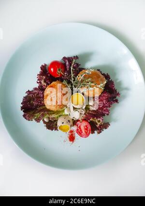 Sur une assiette blanche de côtelettes avec des œufs de caille décorés avec des herbes et des tomates Banque D'Images