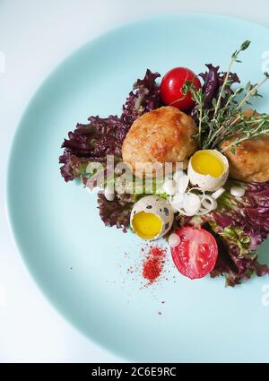 Sur une assiette blanche de côtelettes avec des œufs de caille décorés avec des herbes et des tomates.texture ou fond Banque D'Images
