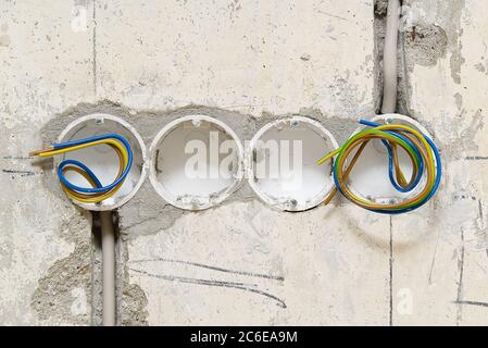 Trous dans un mur en béton pour installer des boîtes en plastique sous les prises. Installation des prises dans un mur en béton et câblage. Banque D'Images