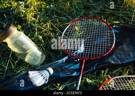 Bouteille d'eau et de citrons et raquette de badminton dans l'herbe de près Banque D'Images