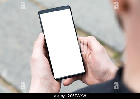L'homme utilise son téléphone mobile en extérieur, gros plan. Image des mains d'un homme utilisant un smartphone mobile. Banque D'Images