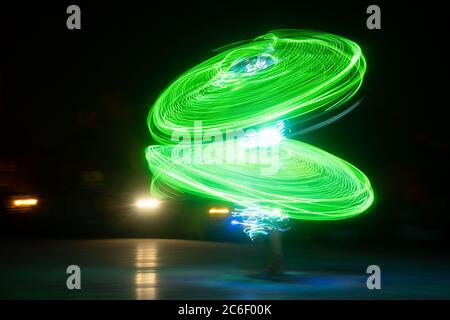 Photo longue exposition d'une personne dansant avec des lumières LED créant un cercle vert Banque D'Images