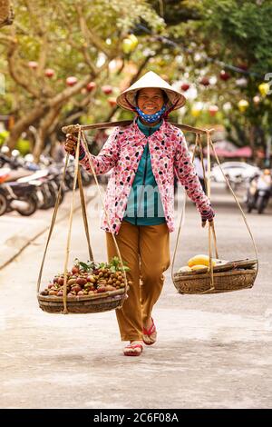Bonne vendeuse de fruits avec chapeau vietnamien en bas de la rue Banque D'Images