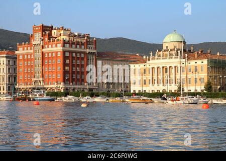 Heure d'or sur le front de mer de Trieste, Italie avec 2 palais imposants et magnifiques : Palazzo Aedes (en rouge) et Palazzo Carciotti. Banque D'Images