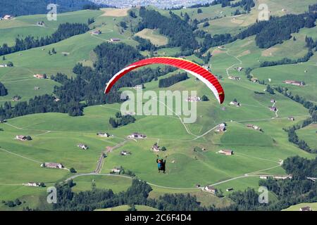 Parapente survolant le champ dans la région montagneuse des Alpes du thé Banque D'Images