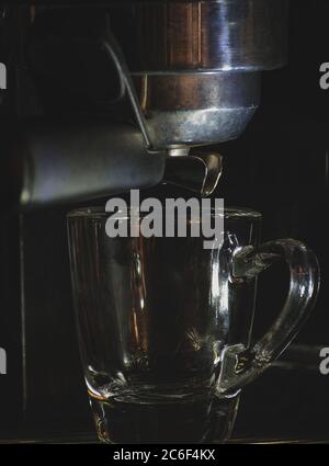 Videz la tasse en verre expresso dans la machine, préparation du café chaud Banque D'Images