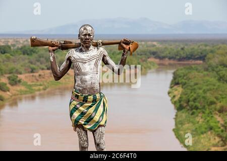 Homme noir peint avec le vieux fusil d'armée Lee–Enfield à boulonner de la tribu Karo / Kara, vallée inférieure d'Omo, zone de Debub Omo, sud de l'Éthiopie, Afrique Banque D'Images