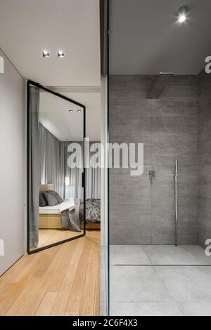 Salle de bains moderne avec douche à l'italienne spacieuse à côté de chambre avec porte en verre Banque D'Images