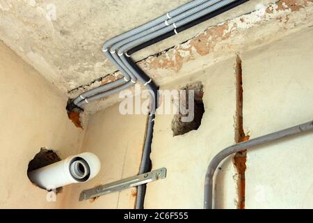 Câbles électriques posés dans une ondulation de protection installée au plafond et au mur dans une pièce en cours de construction. Banque D'Images