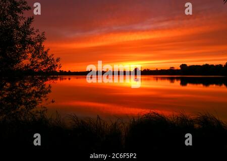 Symétrie du ciel dans un lac au lever du soleil. Nuages qui réfléchissent sur l'eau. Paysage de vacances au bord de la mer. Ambiance calme et relaxante avec une belle couleur Banque D'Images