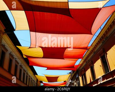 Tente et auvent colorés et bien taillés voile soleil voile protection UV tissu suspendu de l'extérieur au-dessus de la rue urbaine. Centre-ville de la vieille ville. Protection contre le soleil Banque D'Images