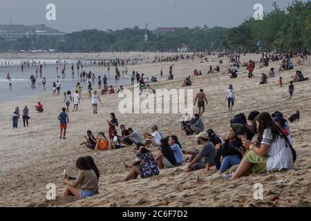 Badung, Bali, Indonésie. 9 juillet 2020. Les troupeaux de personnes à Kuta Beach attendent pour le coucher du soleil. Les autorités locales commencent à rouvrir la célèbre icône touristique de Kuta Beach pour les citoyens de Bali comme une étape du plan ''nouvelle norme'. Kuta Beach est fermée depuis le 30 mars 2020 en raison de préoccupations liées au coronavirus Covid-19. Credit: Dicky Bisinglasi/ZUMA Wire/Alay Live News Banque D'Images