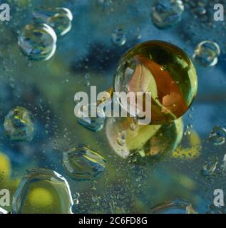 Marbre en verre unique et réflexion avec un fond imprégné de couleur et des gouttelettes d'eau, des bulles, de la solitude. Banque D'Images