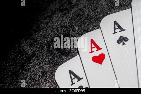 cartes à jouer blanches ace de coeurs, de pique-nains et de clubs dans le coin inférieur droit sur la surface en fonte noire avec l'espace de copie sur le côté gauche, trois de ace Banque D'Images
