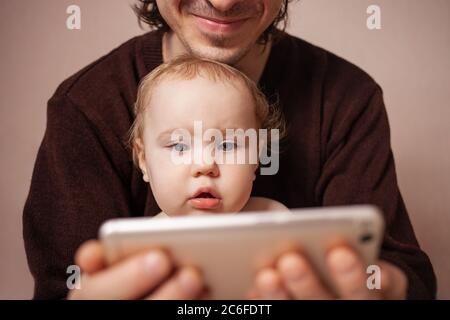 Les parents avec fille regardant la vidéo sur téléphone mobile à la maison, famille jeune couple avec petite fille à l'aide de l'app pour l'éducation ou de contrôle des réseaux sociaux Banque D'Images