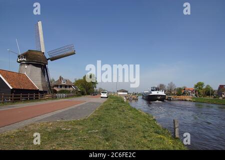 Bateau naviguant dans le canal hollandais (Noordhollandsch kanaal) à travers un pont flottant de la ville d'Alkmaar au village de Koedijk. Moulin à vent (de Sluis Banque D'Images