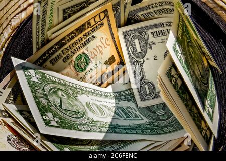 chapeau de paille avec une pile de billets de dollars à l'intérieur, donné à un mendiant réussi Banque D'Images