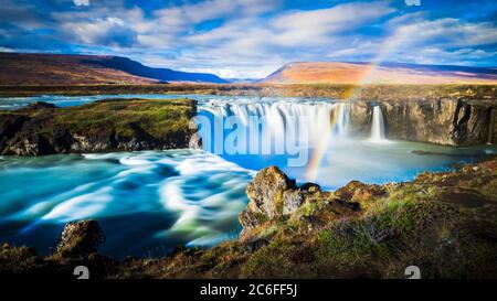 exposition dynamique de longue date panoramique grand angle de la cascade magique godafoss avec arc-en-ciel romantique et collines en arrière-plan à proximité de fossholl, islande Banque D'Images