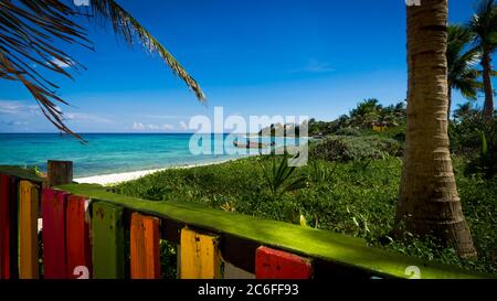 baie des caraïbes avec bateaux de pêcheur en arrière-plan et une clôture en bois colorée en premier plan Banque D'Images