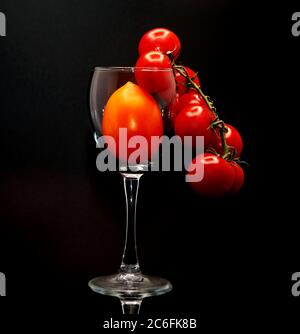 Composition de tomates de différentes tailles et couleurs dans un verre à vin. Produit naturel. Couleur naturelle. Gros plan. Banque D'Images