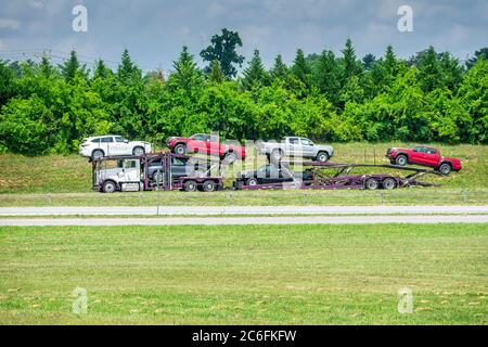 Camion de transport d'automobiles photographié à distance par une chaude journée d'été. Les vagues de chaleur du pavé créent un léger effet de scintillement. Banque D'Images