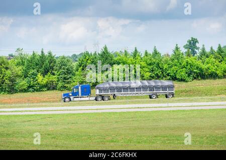 Photo horizontale d'un 18-roues bleu avec un lit couvert en descendant une autoroute du Tennessee. Banque D'Images