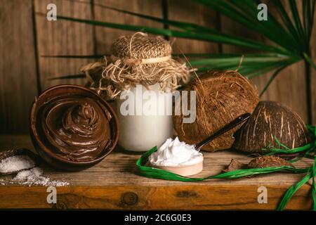 Concept chocolat et noix de coco spa sur fond de bois. Traitement de peau de corps de chocolat. Bol de chocolat fondu et d'huile de coco Banque D'Images