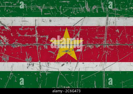 Drapeau surinamais peint sur une surface sale fissurée. Motif national sur une surface de style vintage. Concept rayé et abîmé. Banque D'Images