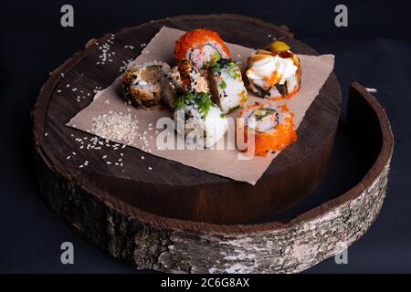 Les petits pains à sushis japonais edp sont sur un plateau en bois, un rouleau de sushi au thon, aux légumes et une sauce unagi, parsemés de graines de sésame Banque D'Images
