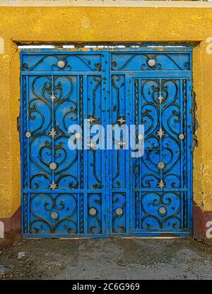 Porte en métal bleu décorée de pièces en filigrane de fer forgé dans les rues arrière d'un village sur la rive ouest du Nil en Égypte Banque D'Images
