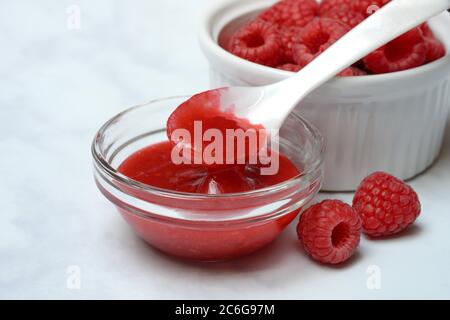 Sauce à la framboise, confiture de framboise dans un bol en verre avec cuillère, framboises, Allemagne Banque D'Images