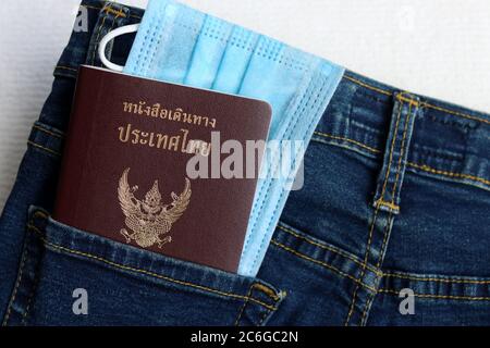 Le tourisme et le voyage concept dans la nouvelle normale après la pandémie de Covid-19 / coronavirus. Passeport thaïlandais avec masque médical dans une poche pour jeans avec espace pour copier. Banque D'Images