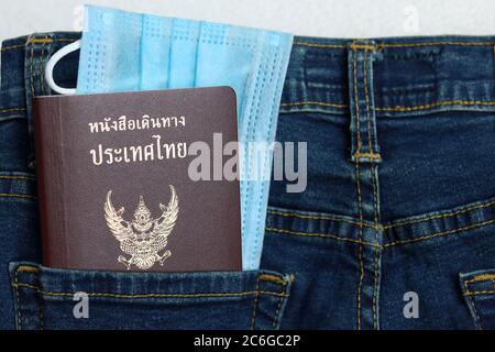 Le tourisme et le voyage concept dans la nouvelle normale après la pandémie de Covid-19 / coronavirus. Passeport thaïlandais avec masque médical dans une poche pour jeans avec espace pour copier. Banque D'Images