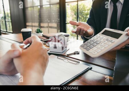 Les agents calculent le taux de paiement du prêt ou le montant des primes d'assurance pour les clients qui viennent contacter l'achat d'une nouvelle maison à l'extérieur Banque D'Images