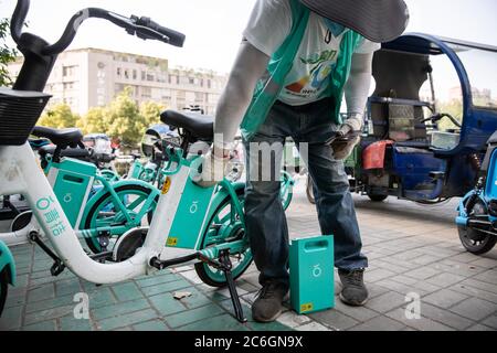 Un chargeur de batterie de vélo partagé change les batteries d'un vélo partagé dans la ville de Hefei, province d'Anhui en Chine orientale, le 4 juin 2020. Banque D'Images