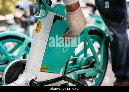 Un chargeur de batterie de vélo partagé change les batteries d'un vélo partagé dans la ville de Hefei, province d'Anhui en Chine orientale, le 4 juin 2020. Banque D'Images