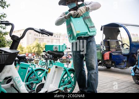 Un chargeur de batterie de vélo partagé change les batteries d'un vélo partagé dans la ville de Hefei, province d'Anhui en Chine orientale, le 4 juin 2020. Banque D'Images