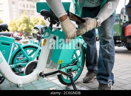 Un chargeur de batterie de vélo partagé change les batteries d'un vélo partagé dans la ville de Hefei, province d'Anhui en Chine orientale, le 4 juin 2020. Banque D'Images