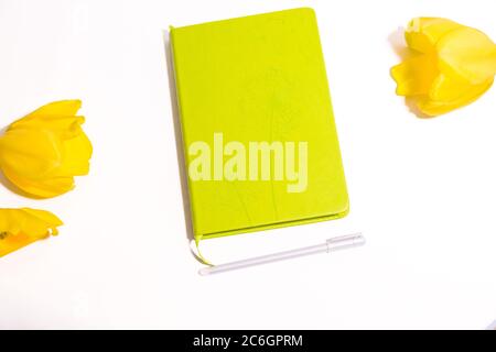 Les fleurs de tulipe de yelow sont sur la table blanche et le journal avec vue de dessus de stylo Banque D'Images