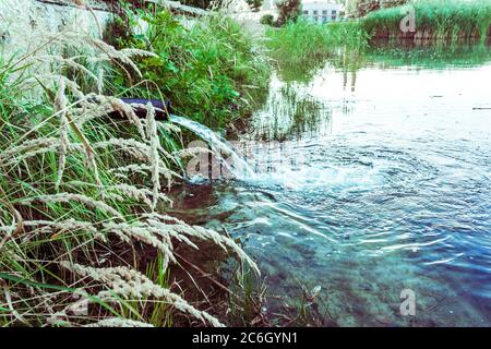 Les flux d'eaux usées dans le lac, rivière. L'eau s'écoule à partir des conduites. La pollution de l'environnement. Banque D'Images