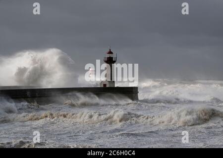 Big White vagues de Piers et phare contre une sombre tempête ciel nuageux. La bouche de la rivière Douro, Porto, Portugal. Banque D'Images