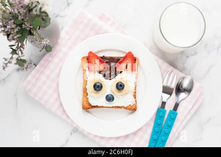 Toast pour le petit déjeuner pour les enfants en forme d'animal mignon avec tartinade chocolat aux noisettes, fromage à la crème et baies servis avec un verre de lait. Vue de dessus. Chi Banque D'Images