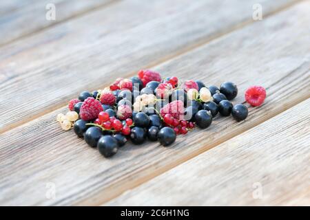 Fruits de baies comme les fraises, les raisins de Corinthe, les framboises et les raisins de Corinthe noirs sur fond de table en bois. Mise au point douce Banque D'Images