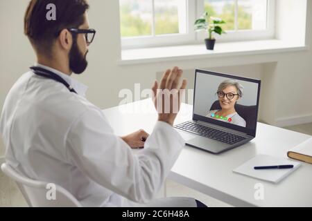 Médecin en ligne. La patiente âgée informe le médecin des symptômes de la maladie à l'aide d'un ordinateur portable de consultation par chat vidéo clinique virtuelle. Banque D'Images