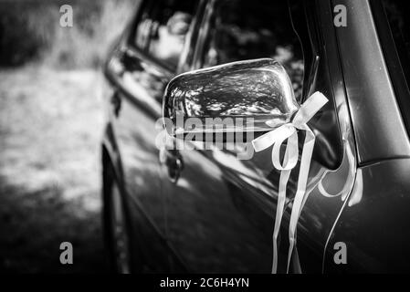 Miroir de voiture de mariage décoré avec ruban. Photo en noir et blanc. Mise au point sélective. DOF peu profond Banque D'Images