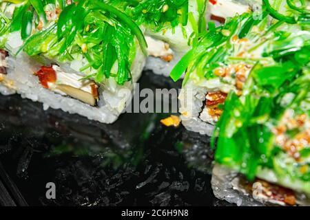 Petits pains avec du poisson, du fromage et des algues vertes. Un plat traditionnel japonais. Gros plan Banque D'Images