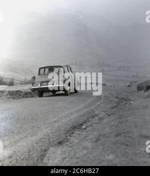Années 1960, historique, une Ford Anglia 105E Deluxe voiture garée sur une route de gravier à flanc de colline au milieu d'une brumeuse dales du Yorkshire, Angleterre, Royaume-Uni. Banque D'Images