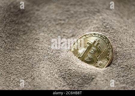 Cette image abstraite montre les bitcoins partiellement enfouis vus dans le sable de silicium. Le concept de cette image est que le silicium est la pierre angulaire. Banque D'Images