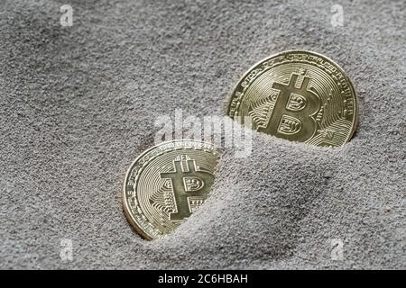 Cette image abstraite montre les bitcoins partiellement enfouis vus dans le sable de silicium. Le concept de cette image est que le silicium est la pierre angulaire. Banque D'Images